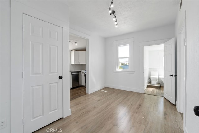 interior space with a textured ceiling, light hardwood / wood-style flooring, and track lighting