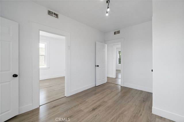 unfurnished bedroom with light hardwood / wood-style floors and multiple windows