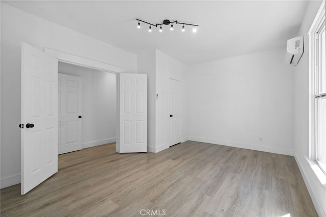 unfurnished bedroom with light hardwood / wood-style flooring, a closet, and a wall mounted AC