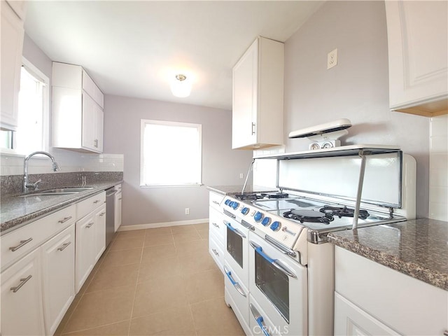 kitchen featuring dishwasher, sink, range with two ovens, white cabinets, and dark stone counters