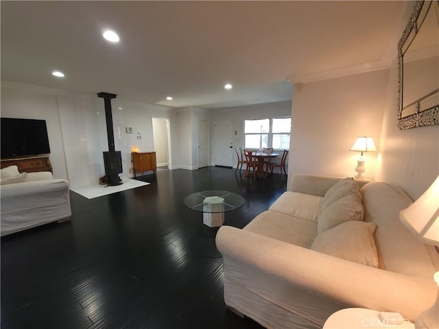 living room featuring dark wood-type flooring, a wood stove, and ornamental molding