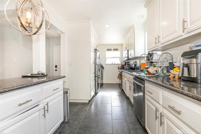 kitchen featuring decorative light fixtures, white cabinets, stainless steel appliances, and dark stone counters