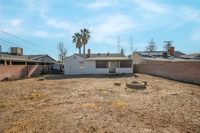 back of property with a sunroom and an outdoor fire pit