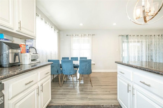 dining room with a wealth of natural light, hardwood / wood-style floors, and a notable chandelier