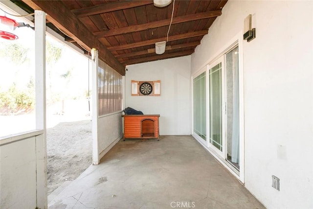 unfurnished sunroom with vaulted ceiling with beams, plenty of natural light, and wooden ceiling