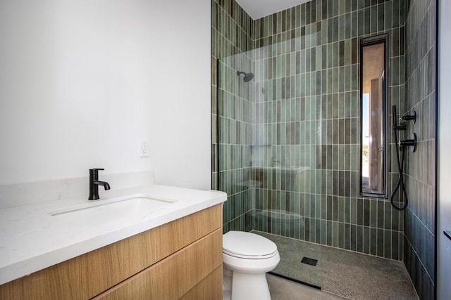 bathroom featuring toilet, vanity, and a tile shower