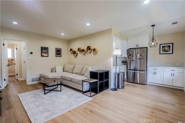 living room featuring light wood-type flooring, visible vents, and recessed lighting