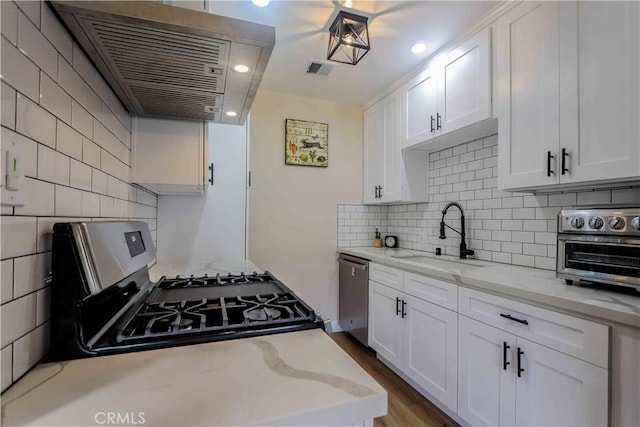 kitchen featuring sink, light stone countertops, white cabinets, and appliances with stainless steel finishes