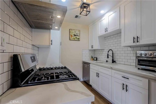 kitchen with a toaster, appliances with stainless steel finishes, white cabinets, and a sink