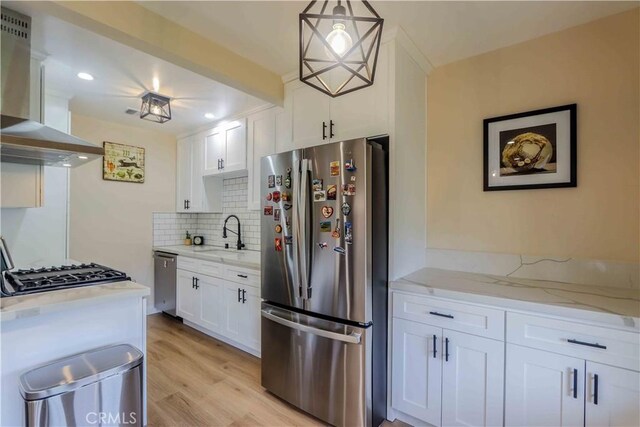 kitchen featuring pendant lighting, stainless steel appliances, island range hood, and white cabinets