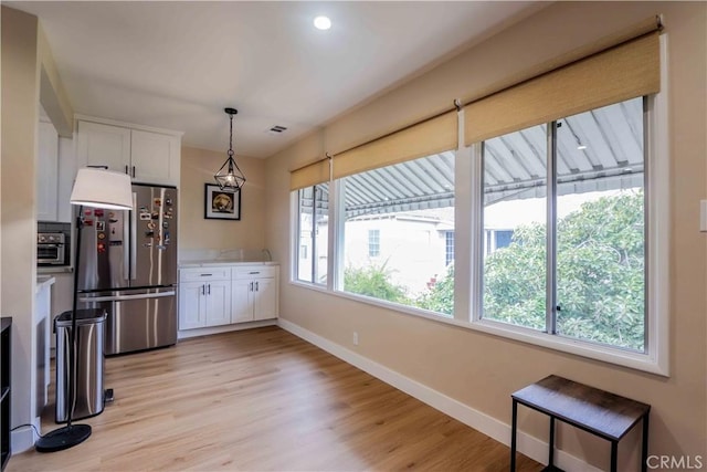 kitchen featuring baseboards, light wood-style floors, light countertops, white cabinets, and freestanding refrigerator