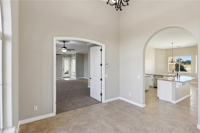 carpeted spare room with ceiling fan with notable chandelier and sink