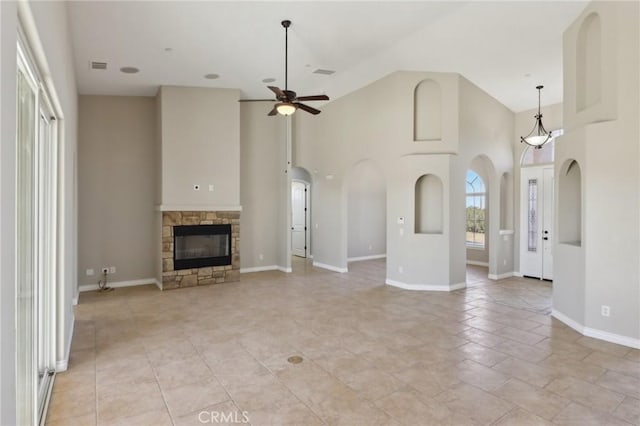 unfurnished living room featuring ceiling fan, a high ceiling, and a stone fireplace