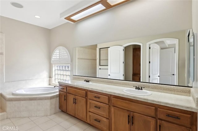 bathroom with tiled bath, vanity, and tile patterned floors