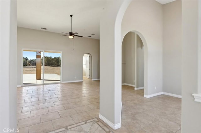 tiled empty room with ceiling fan and a towering ceiling