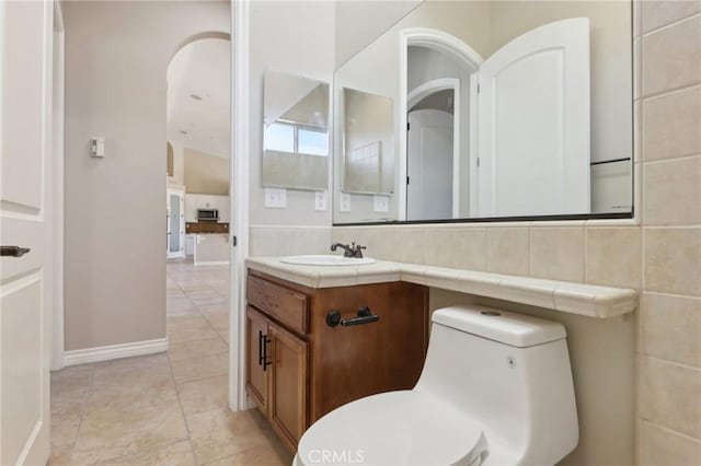 bathroom with toilet, vanity, and decorative backsplash