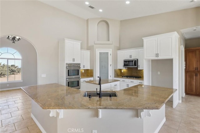 kitchen featuring white cabinets, appliances with stainless steel finishes, sink, backsplash, and light tile patterned flooring