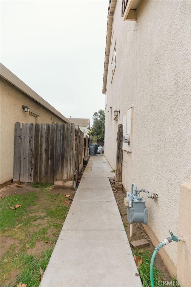 view of side of property with fence and stucco siding