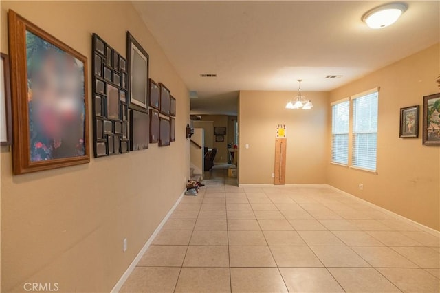 empty room with an inviting chandelier and light tile patterned floors