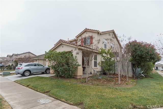 view of front of home with an attached garage, driveway, a tiled roof, stucco siding, and a front yard