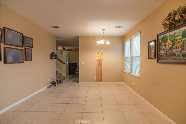 empty room featuring light tile patterned flooring and ceiling fan with notable chandelier