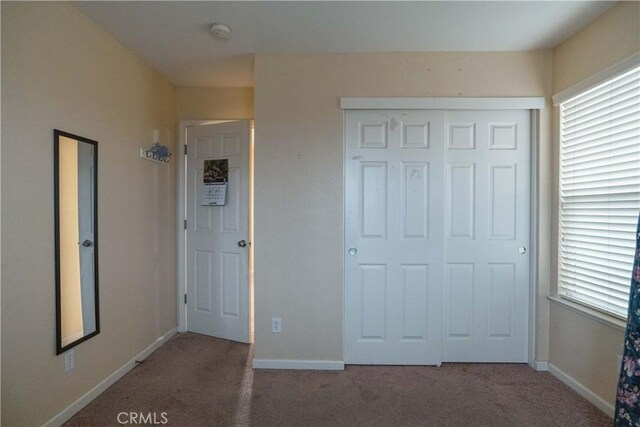 unfurnished bedroom with a closet and dark carpet