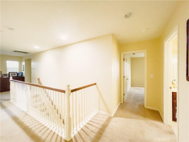 corridor featuring light carpet, visible vents, an upstairs landing, and baseboards