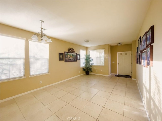 unfurnished room with light tile patterned floors, baseboards, and an inviting chandelier