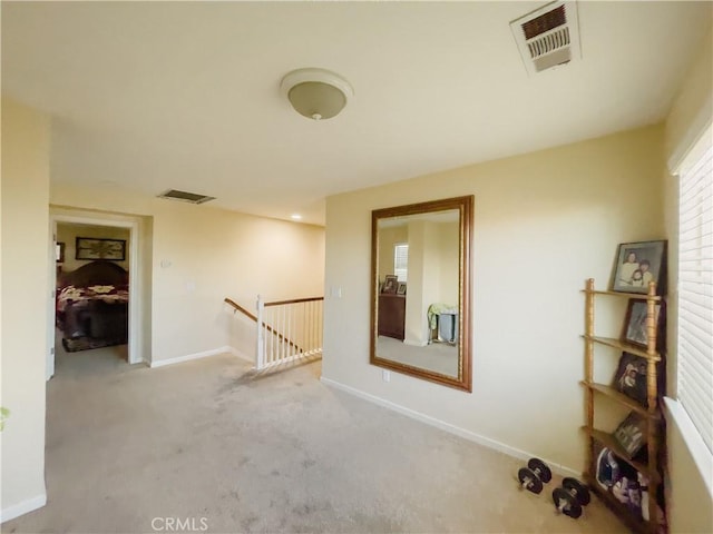 unfurnished room with carpet, visible vents, and baseboards