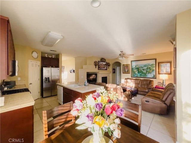 dining room featuring a tile fireplace, ceiling fan, and light tile patterned floors