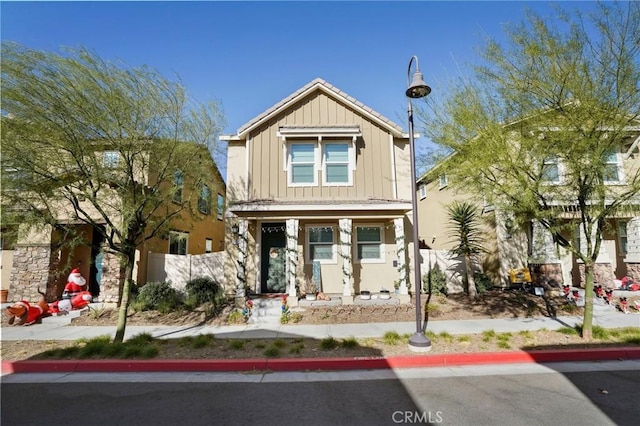 craftsman inspired home featuring covered porch, board and batten siding, and fence