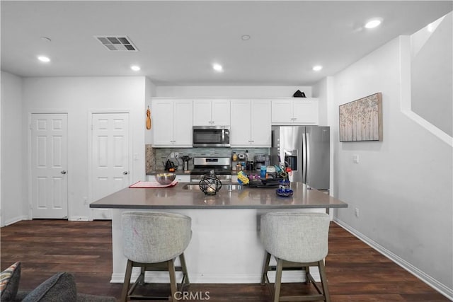 kitchen with dark countertops, visible vents, stainless steel appliances, and a breakfast bar area