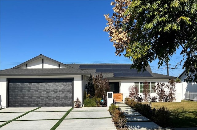 view of front of property with a garage, a front yard, and solar panels