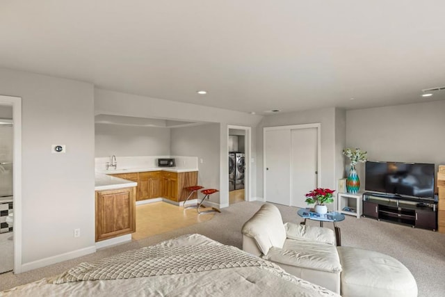 living room featuring light colored carpet, sink, and independent washer and dryer