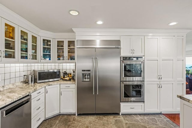 kitchen with light stone countertops, backsplash, appliances with stainless steel finishes, and white cabinetry