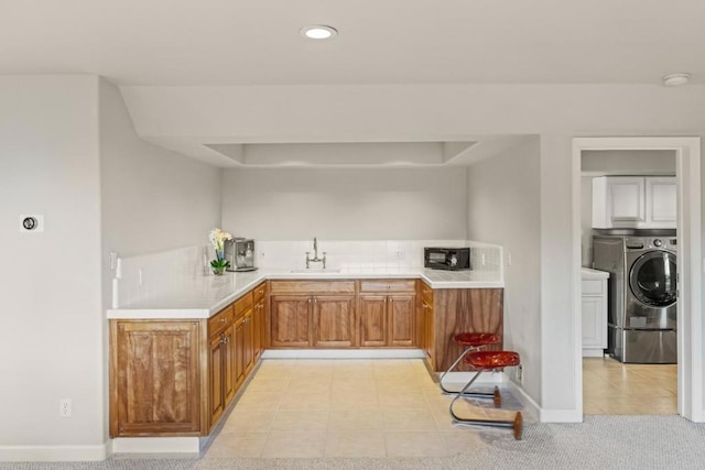 kitchen with sink, light tile patterned floors, and separate washer and dryer