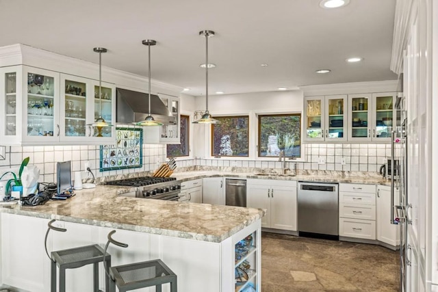 kitchen featuring pendant lighting, kitchen peninsula, stainless steel appliances, white cabinets, and ventilation hood