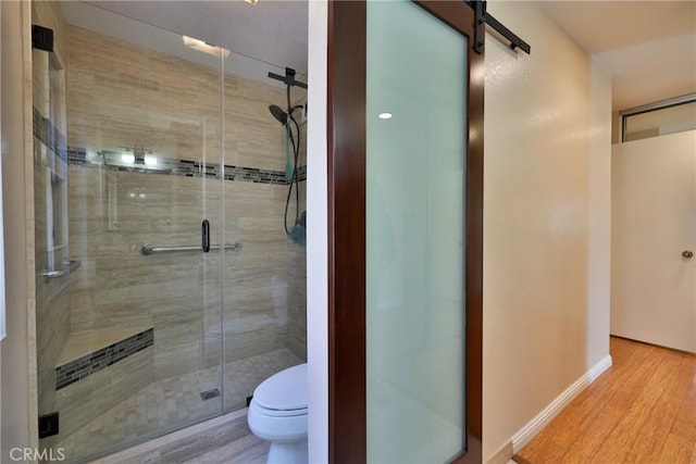 bathroom with toilet, hardwood / wood-style flooring, and an enclosed shower