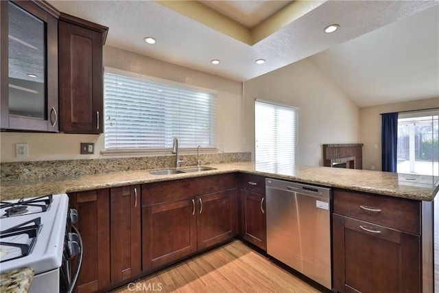 kitchen with sink, kitchen peninsula, vaulted ceiling, stainless steel dishwasher, and light hardwood / wood-style flooring