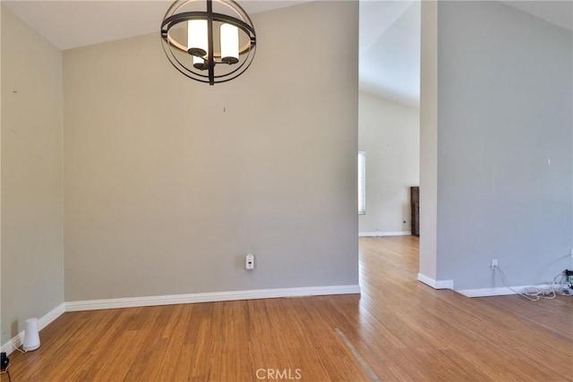 unfurnished room featuring vaulted ceiling, a notable chandelier, and light wood-type flooring