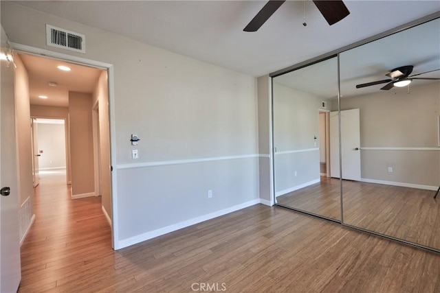 unfurnished bedroom featuring a closet, hardwood / wood-style flooring, and ceiling fan