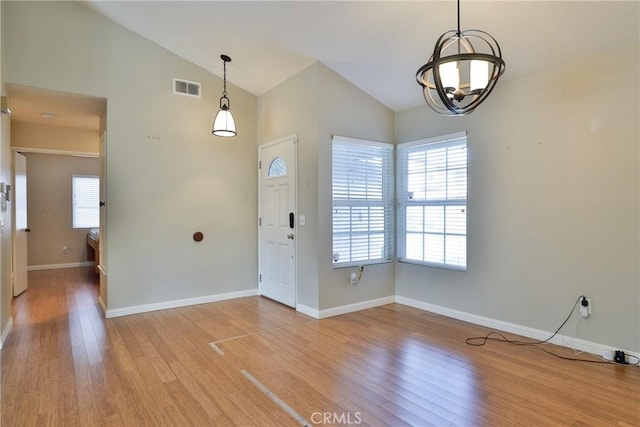 entrance foyer featuring light wood-type flooring, vaulted ceiling, and a chandelier