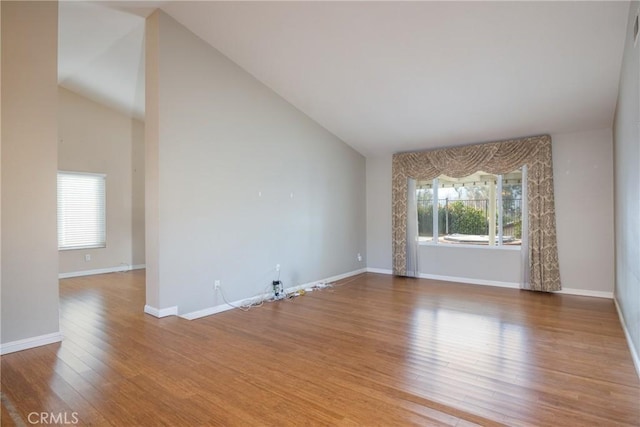 spare room with hardwood / wood-style floors and high vaulted ceiling