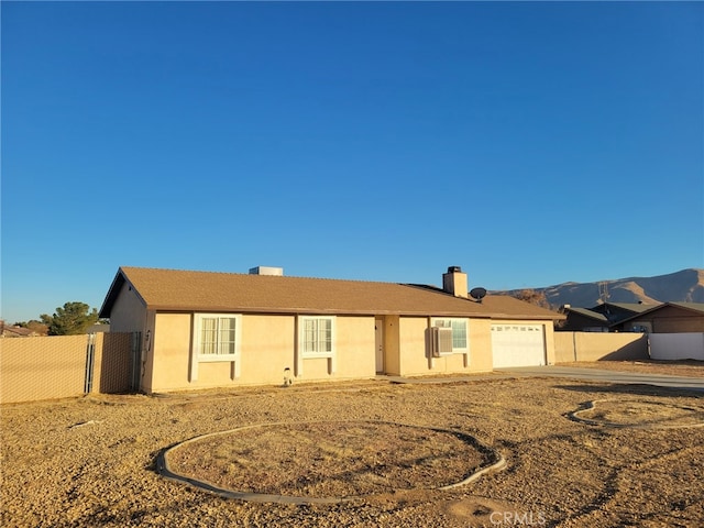 single story home featuring stucco siding, a mountain view, a garage, and fence