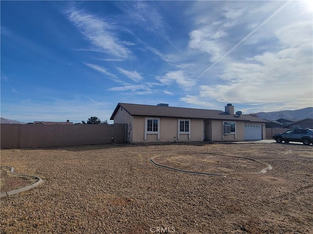 single story home with a garage, stucco siding, and fence