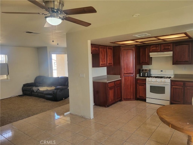 kitchen with light tile patterned floors, white gas stove, plenty of natural light, and ceiling fan