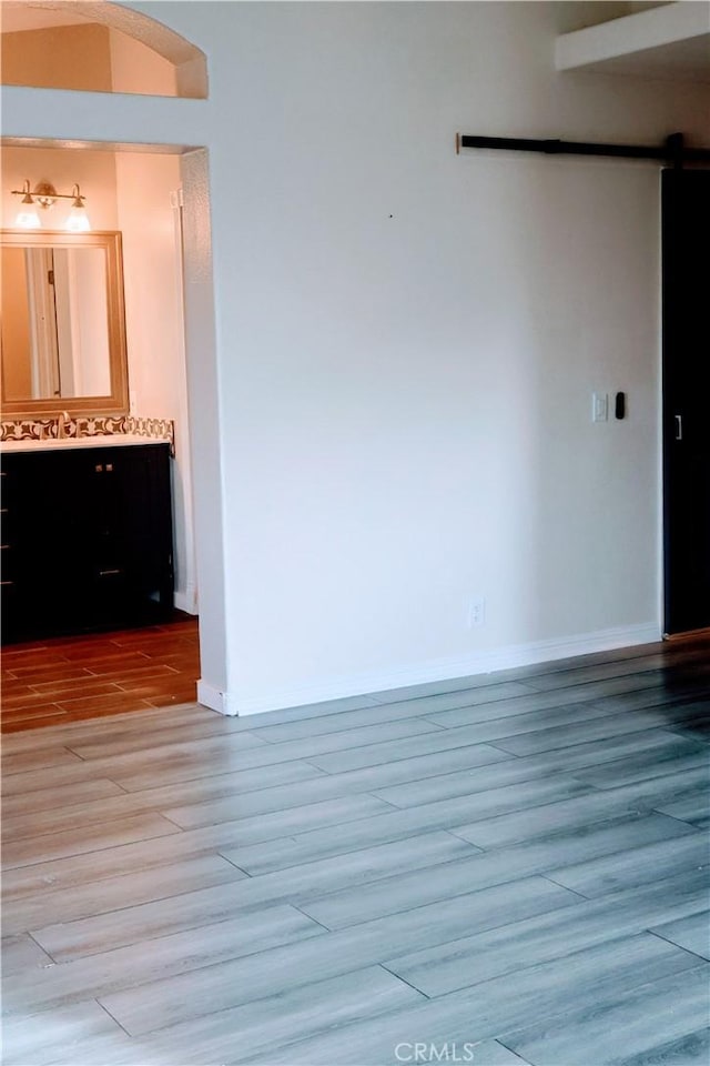 empty room with a barn door and light hardwood / wood-style floors