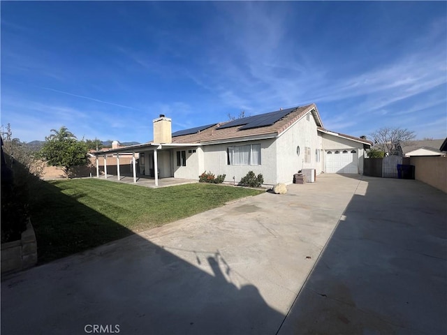 back of property featuring a garage, a yard, and solar panels