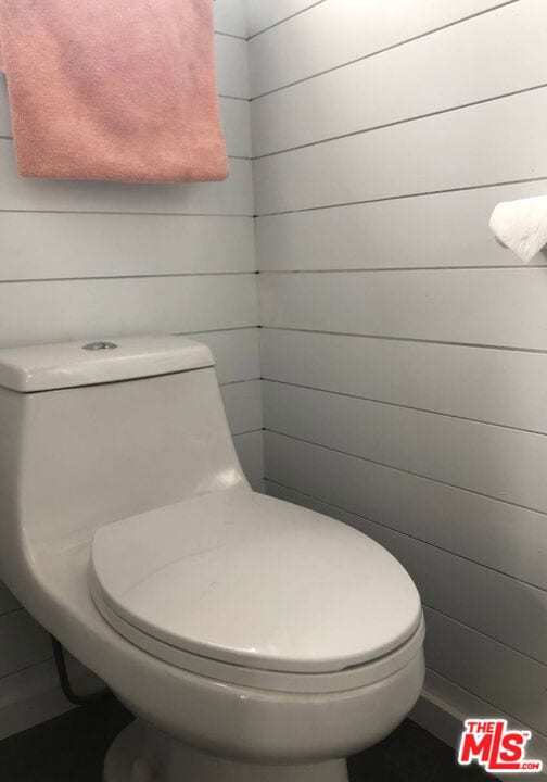 bathroom featuring toilet and wood walls