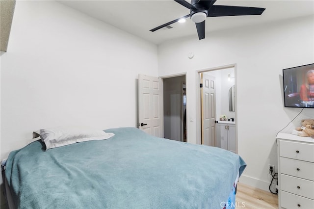 bedroom with light wood-type flooring, ceiling fan, and ensuite bathroom